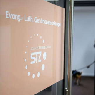 Die Tür mit dem Logo des Sozialen Teilhabe Zentrum ist leicht geöffnet. 